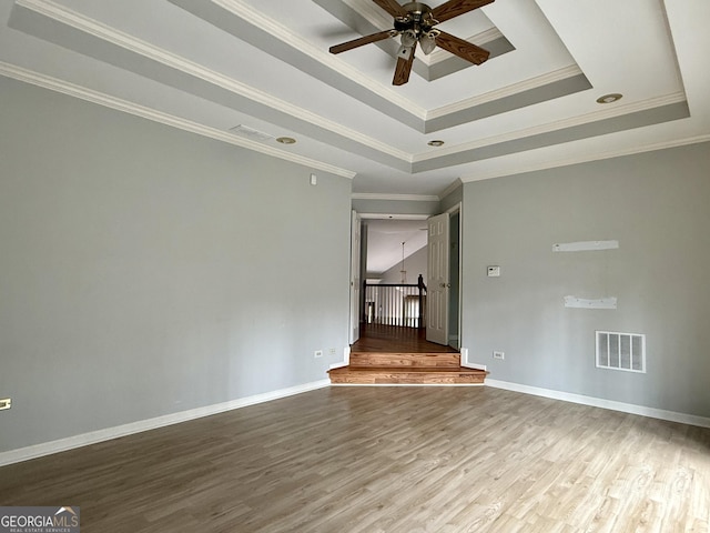 empty room featuring crown molding, hardwood / wood-style floors, ceiling fan, and a tray ceiling