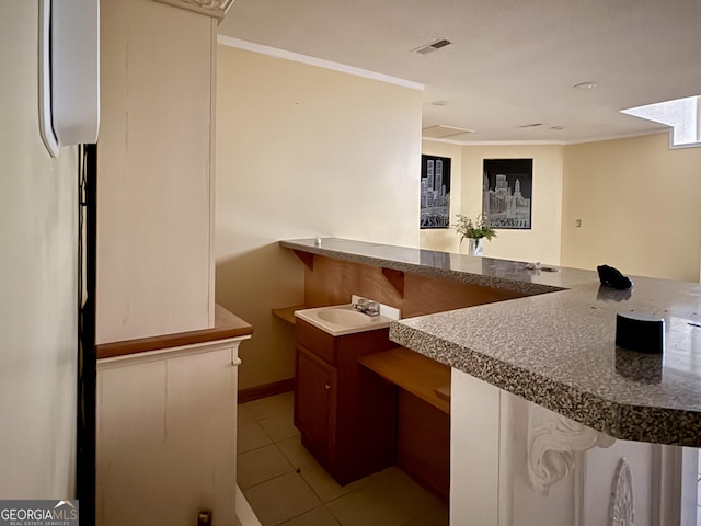 kitchen with sink, crown molding, and light tile patterned floors