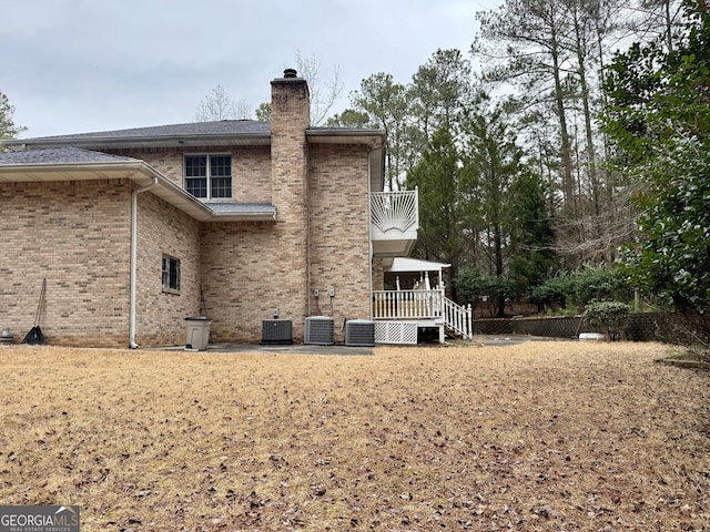 rear view of property with cooling unit and a balcony