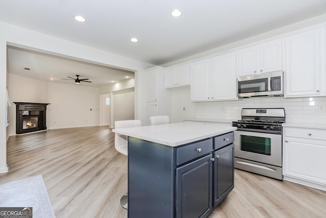 kitchen featuring white cabinetry, appliances with stainless steel finishes, backsplash, and light hardwood / wood-style flooring