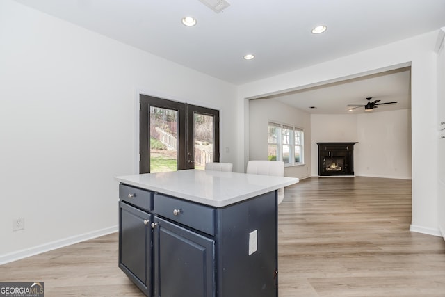 kitchen with ceiling fan, a center island, and light hardwood / wood-style flooring