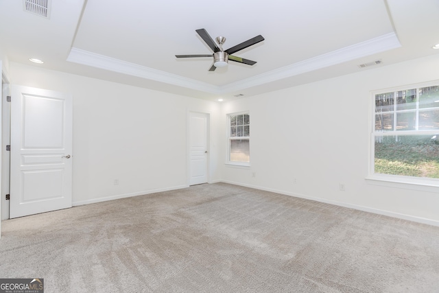 carpeted empty room featuring crown molding, a tray ceiling, and ceiling fan