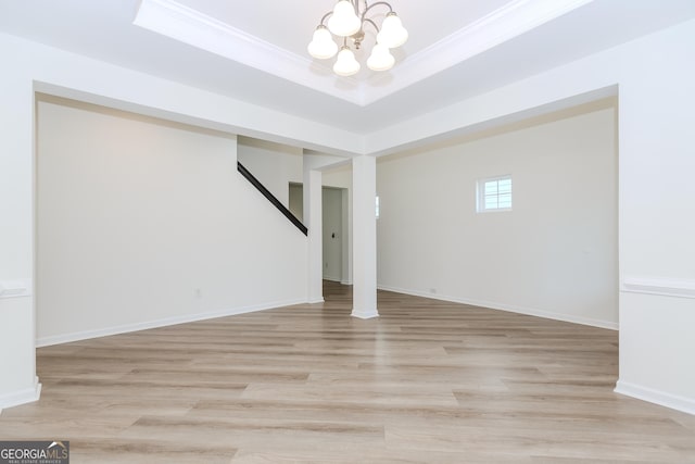 basement with crown molding, an inviting chandelier, and light hardwood / wood-style flooring