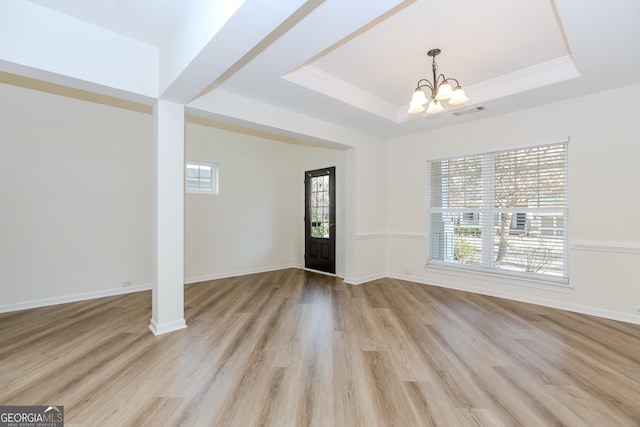 entryway with a raised ceiling, ornamental molding, a notable chandelier, and light hardwood / wood-style flooring