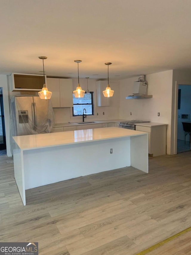 kitchen with pendant lighting, sink, appliances with stainless steel finishes, white cabinetry, and ventilation hood