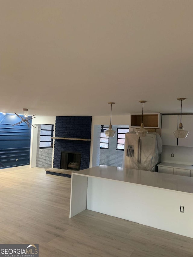 kitchen with pendant lighting, refrigerator with ice dispenser, a fireplace, and hardwood / wood-style floors