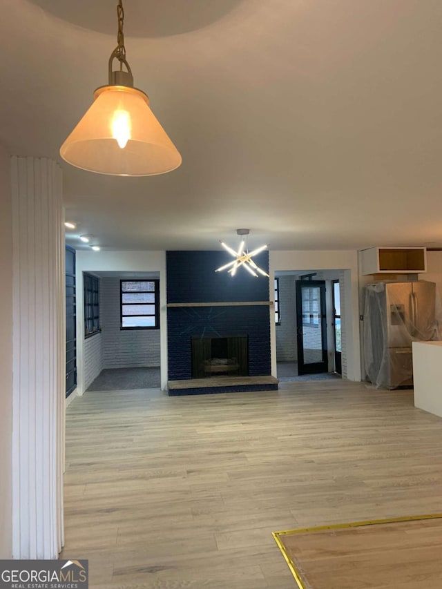 unfurnished living room with wood-type flooring and a brick fireplace