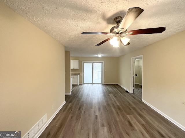 unfurnished living room featuring ceiling fan, a textured ceiling, and dark hardwood / wood-style flooring