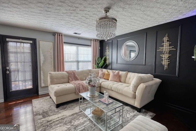 living room featuring a notable chandelier, a textured ceiling, and dark hardwood / wood-style flooring