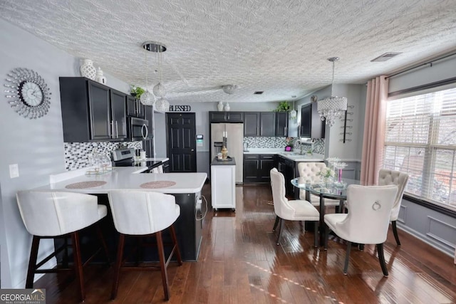 kitchen with hanging light fixtures, appliances with stainless steel finishes, sink, and kitchen peninsula