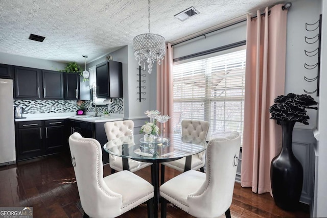 dining room with sink, dark hardwood / wood-style floors, and a textured ceiling