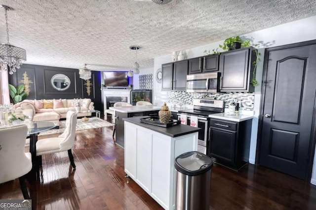 kitchen with hanging light fixtures, appliances with stainless steel finishes, backsplash, and dark hardwood / wood-style flooring