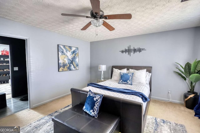 bedroom with ceiling fan, carpet floors, and a textured ceiling