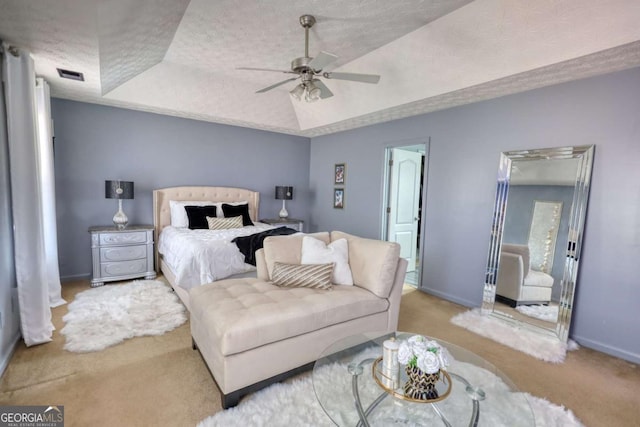 bedroom with ceiling fan, light colored carpet, a raised ceiling, and a textured ceiling