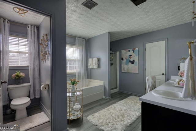 bathroom with vanity, hardwood / wood-style floors, a tub, and a textured ceiling