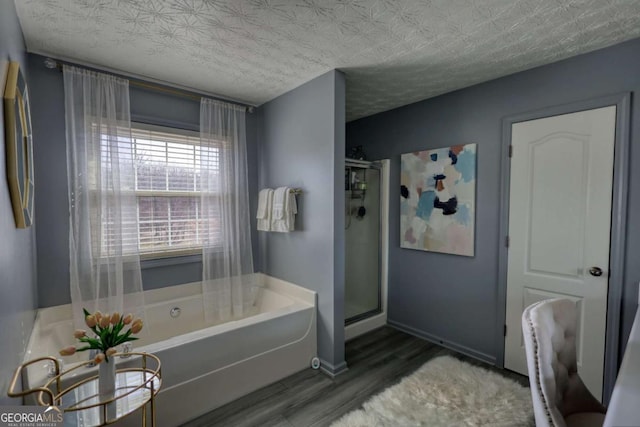 bathroom with plus walk in shower, hardwood / wood-style floors, and a textured ceiling