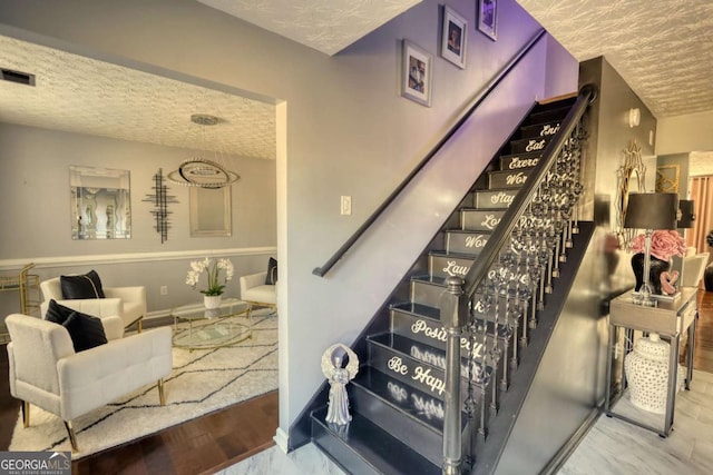 stairway with hardwood / wood-style floors and a textured ceiling