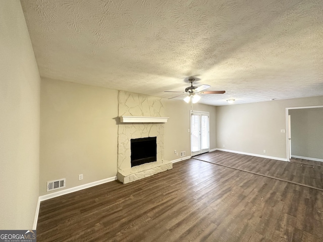unfurnished living room featuring dark hardwood / wood-style flooring, a textured ceiling, a fireplace, and ceiling fan