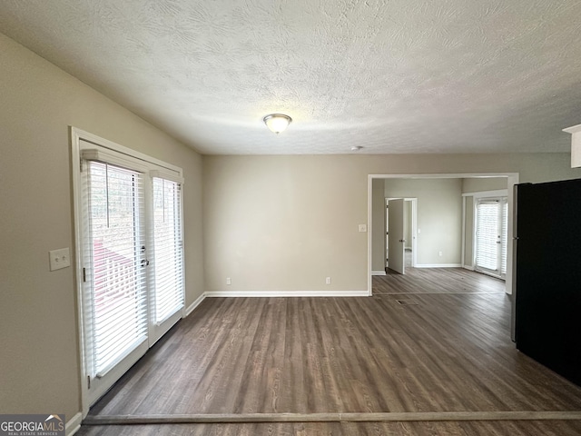 spare room featuring dark hardwood / wood-style flooring and a textured ceiling