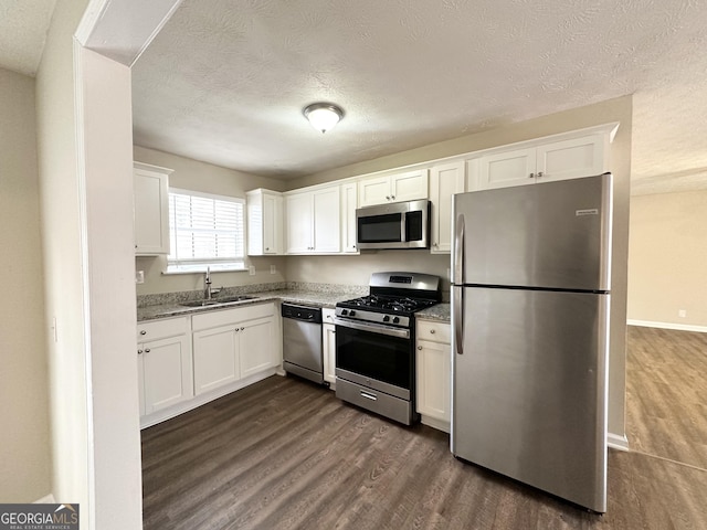 kitchen featuring appliances with stainless steel finishes, sink, white cabinets, and dark hardwood / wood-style flooring