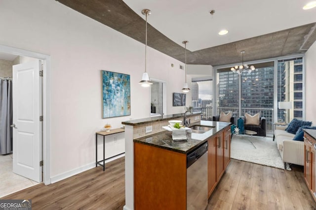 kitchen with stainless steel dishwasher, light hardwood / wood-style floors, hanging light fixtures, and dark stone countertops