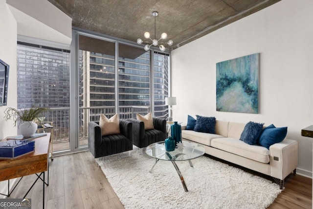 living room with a healthy amount of sunlight, hardwood / wood-style floors, a notable chandelier, and a wall of windows