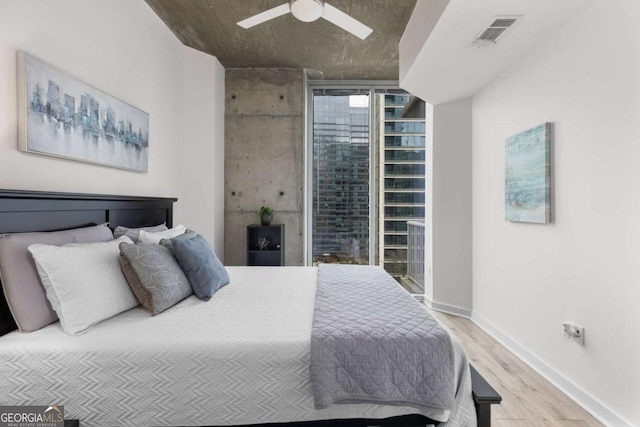 bedroom featuring floor to ceiling windows, hardwood / wood-style floors, and ceiling fan