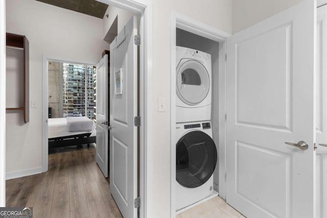 clothes washing area featuring stacked washer and clothes dryer and light hardwood / wood-style flooring