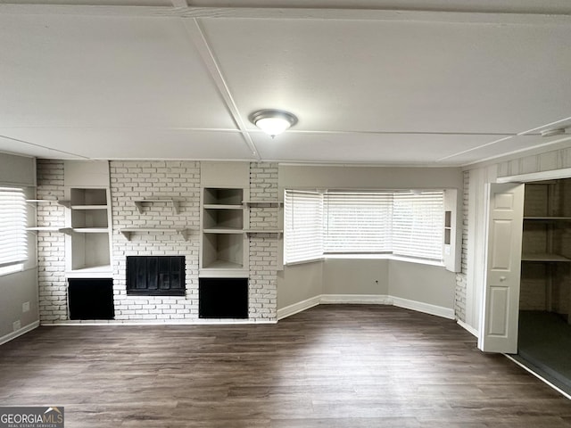 unfurnished living room featuring dark wood-type flooring and built in shelves