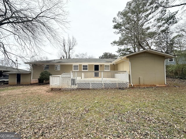 rear view of house with a wooden deck and a yard