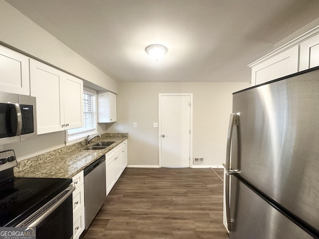 kitchen with sink, appliances with stainless steel finishes, dark stone countertops, dark hardwood / wood-style floors, and white cabinets