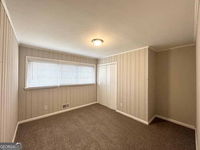 unfurnished room featuring crown molding and dark colored carpet