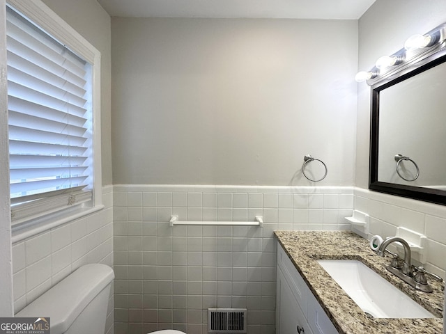 bathroom featuring vanity, tile walls, and toilet