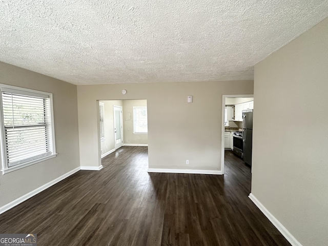 spare room featuring dark hardwood / wood-style flooring and a textured ceiling