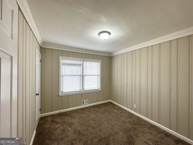 spare room featuring ornamental molding and dark carpet