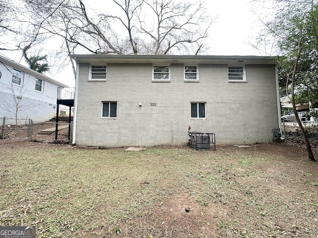 rear view of house featuring cooling unit and a yard