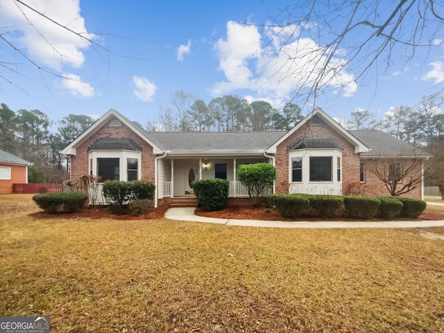 ranch-style home featuring a front lawn and covered porch