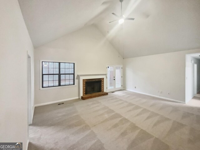 unfurnished living room with ceiling fan, light colored carpet, high vaulted ceiling, and a brick fireplace