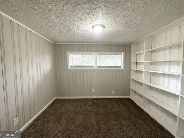 carpeted spare room featuring a textured ceiling and wood walls