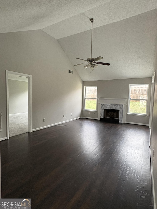 unfurnished living room featuring a fireplace, a textured ceiling, dark wood-type flooring, and ceiling fan