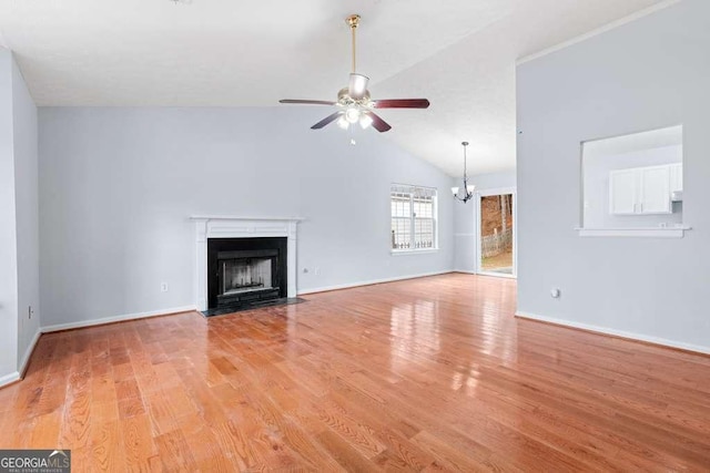 unfurnished living room featuring ceiling fan with notable chandelier, high vaulted ceiling, and light hardwood / wood-style floors