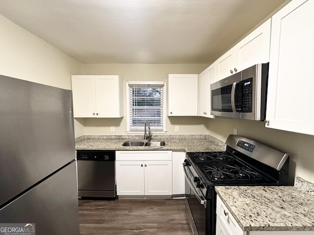 kitchen with stainless steel appliances, white cabinetry, sink, and light stone counters