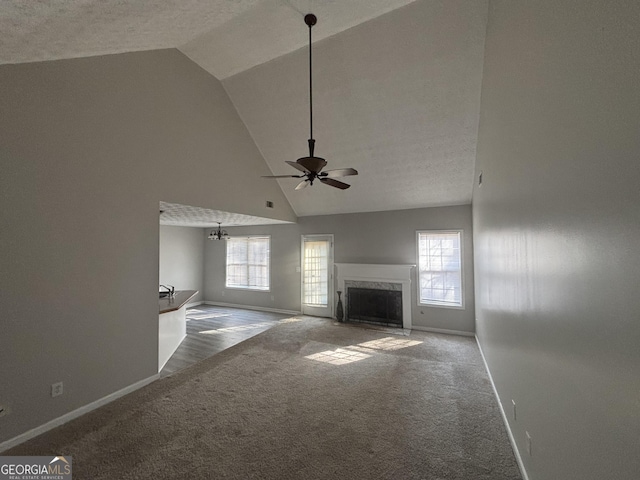 unfurnished living room with ceiling fan, high vaulted ceiling, carpet flooring, and a high end fireplace