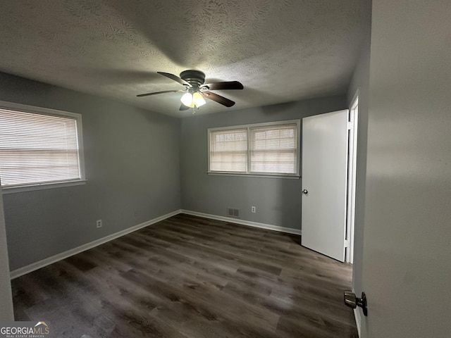 spare room with plenty of natural light, dark wood-type flooring, and ceiling fan