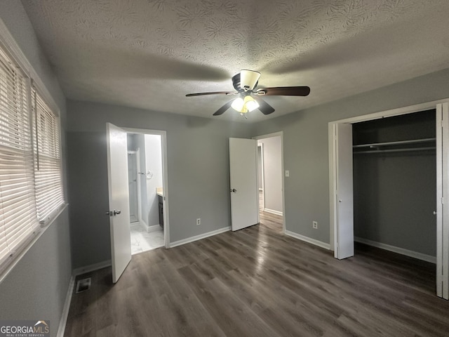 unfurnished bedroom with dark wood-type flooring, ceiling fan, a closet, and a textured ceiling