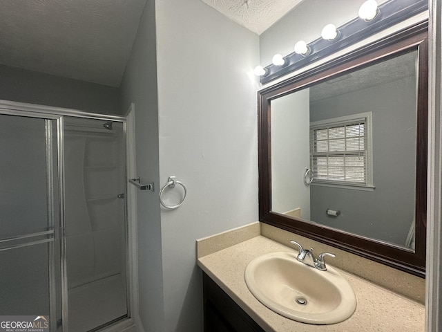 bathroom with an enclosed shower, vanity, and a textured ceiling