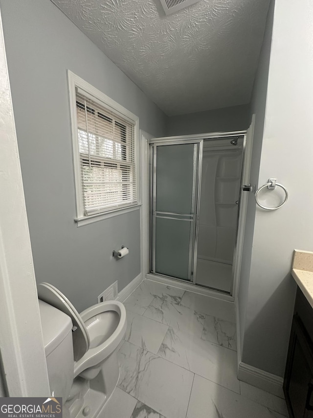 bathroom with vanity, toilet, an enclosed shower, and a textured ceiling