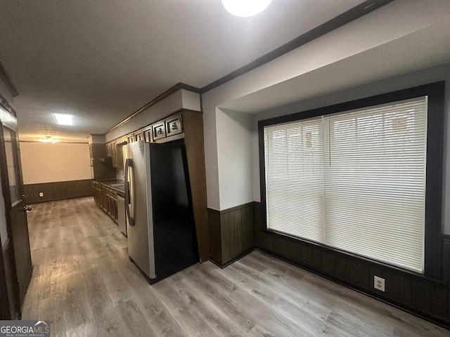 kitchen featuring stainless steel fridge, light hardwood / wood-style flooring, and wood walls