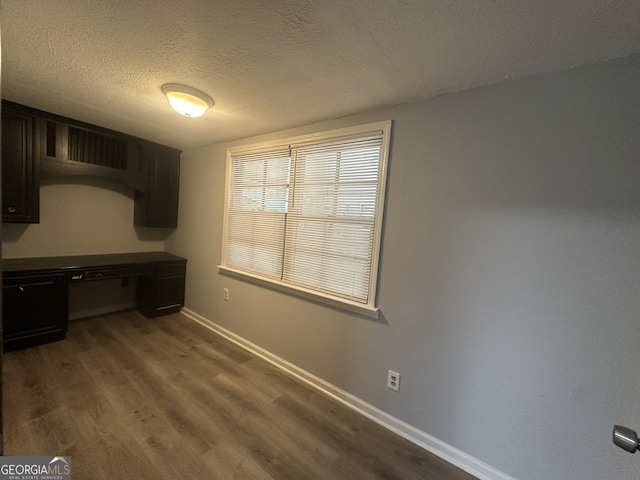 interior space with dark hardwood / wood-style flooring, built in desk, and a textured ceiling