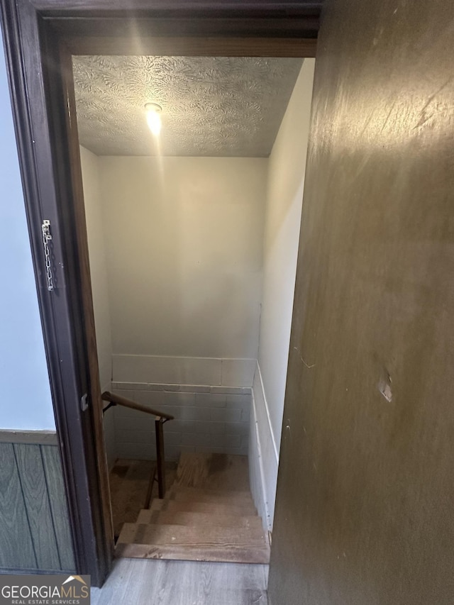 stairway with hardwood / wood-style flooring and a textured ceiling